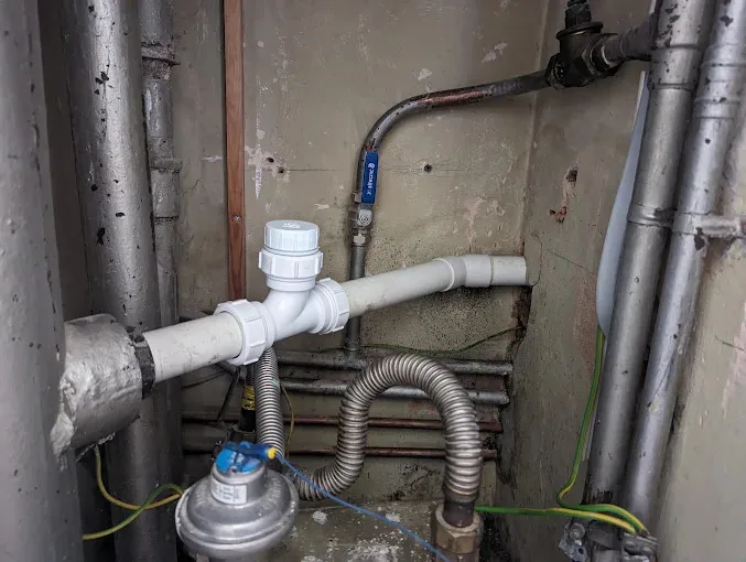 New white pipework run with compression fittings and an isolation valve in a service cupboard